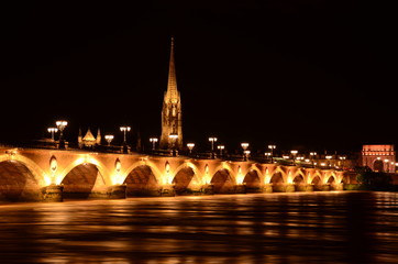 Fototapeta na wymiar Stone bridge of Bordeaux city by night with basilica background
