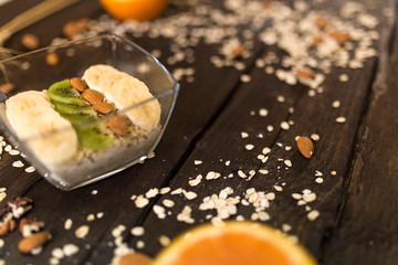 proper nutrition, fitness food, water, fruit, green apple, banana, orange, nuts, wheat. program of diet, dumbbells. The concept of healthy food on a dark wooden background for advertising your text