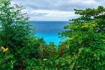 Obraz premium enchanting natural wild landscape with rocky mountains overgrown dense green jungle tree, palm and clear azure water of sea ocean