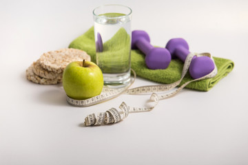 proper nutrition, fitness food, a glass of water, a green apple, wheat bread, a diet program, dumbbells. concept of healthy food on a white background for advertising your text