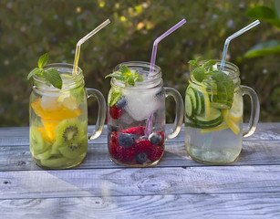 Jars with fruit infused water in summer garden