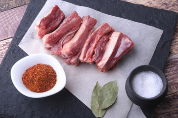 Raw fresh meat, uncooked lamb or beef ribs with pepper, garlic, salt and spices on dark stone background, Ready for cooking. copy space.