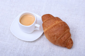Classic espresso in white cup and croissant on white background. Top view.