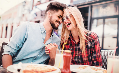 Loving couple sitting in the cafe and eating pizza. Consumerism, food, lifestyle concept