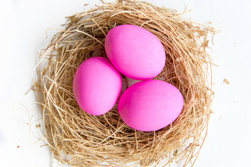 Naklejka na ściany i meble Pink colored Easter eggs in nest on wooden background, selective focus image. Happy Easter card 