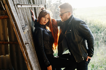 Fototapeta na wymiar stylish glamorous couple in black leather jackets posing in a hangar