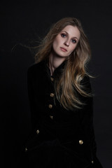 Full length model in black dress posing sitting on dark background