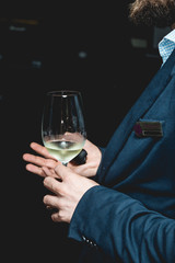 man holds glass of wine. people consider the color of the wine and try how it smells in different glasses