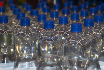 background - plastic bottles with drinking water with blue stoppers