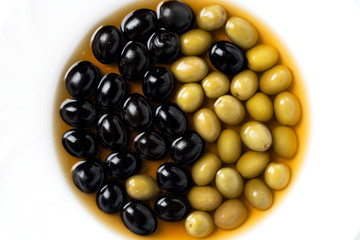 Olives and olives in a white plate in the form of yin-yang. View from above.