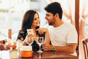 Couple at restaurant looking at his smart phone