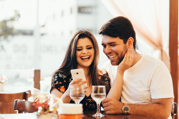 Couple at restaurant looking at his smart phone