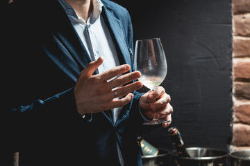 man holds glass of wine. people consider the color of the wine and try how it smells in different glasses