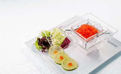 Red caviar in ice close up with lime. Sea food. wooden.