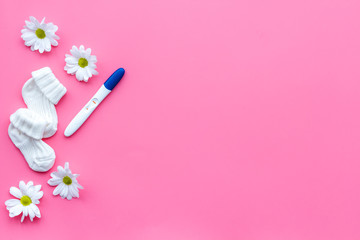 Pregnancy and preparation for childbirth. Pregnancy test near flowers on pink background top view space for text