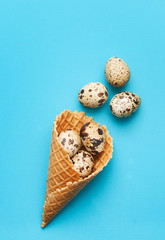 Quail eggs in waffle cup on blue background.