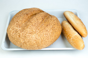 Many mixed breads and rolls of baked bread, on wooden table background.