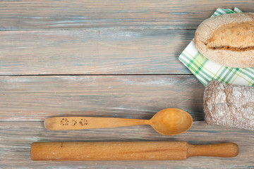 Many mixed breads and rolls of baked bread on wooden table background.