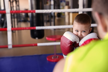 Little boy training with coach in boxing ring