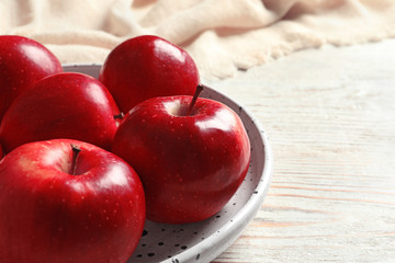 Plate with ripe red apples on wooden background