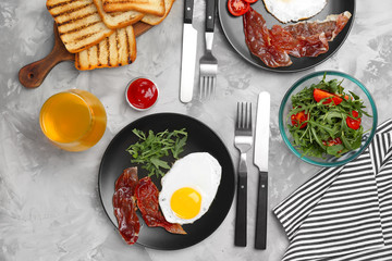 Plate with fried egg, bacon and arugula on table