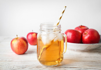 Mason jar with fresh apple juice on wooden table