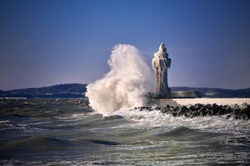 Fototapeta na wymiar frozen lighthouse and pier on stormy winter day