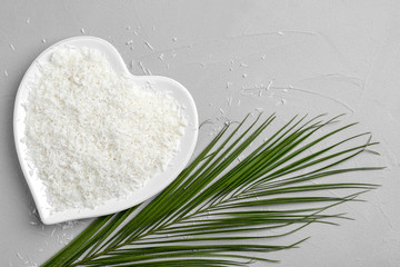 Heart-shaped plate with fresh coconut flakes on grey background