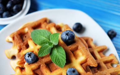Homemade waffles with blueberries in plate on wooden table