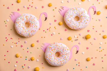 Fresh tasty donuts, candies and sprinkles on color background