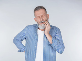Man suffering from toothache on light background