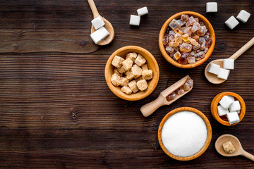 Sugar types. Cane, refind, granulated, cubes, candy sugar. Dark wooden background top view copy space