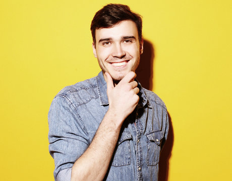 Portrait of young smiling man standing against yellow background