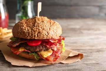 Tasty burger with bacon on wooden table