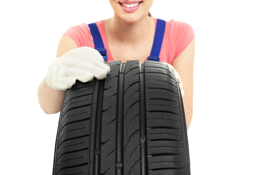Female mechanic with car tire on white background, closeup