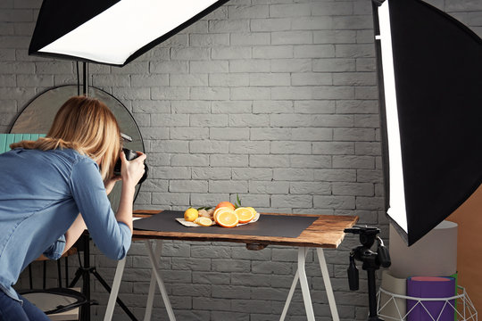 Woman taking photo of food with professional camera in studio