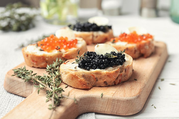 Sandwiches with black and red caviar on wooden board