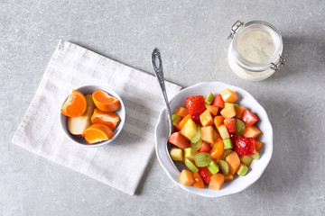 Bowl with fresh fruit salad on grey background