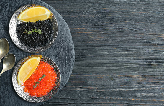 Plates with black and red caviar on wooden background