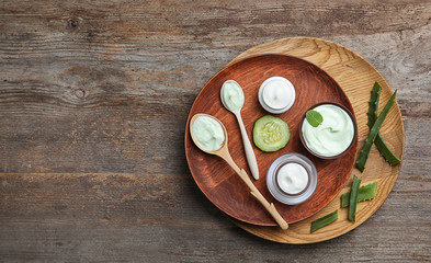 Composition with body cream in jars on wooden background, top view