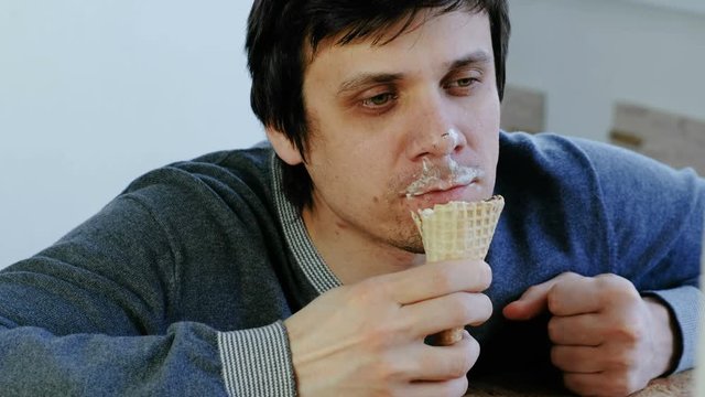 Closeup of young lousy man eats ice cream.