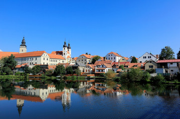 Fototapeta na wymiar A fairy tale castle and old town with beautiful mirror reflections on smooth lake water under clear blue sky in Telc, a UNESCO world heritage site in Czech Republic, Europe 