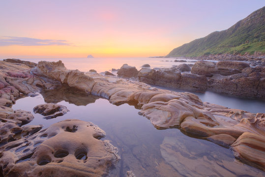 Beautiful scenery of dawning sky by rocky seashore in northern Taiwan (long exposure effect) With beautiful and tranquil reflection of water