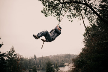 Man swinging from forest rope swing