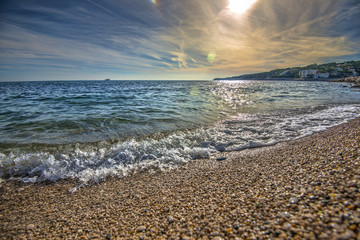 Surreal, rocky beach with clear ocean waves at sunset on southern coast of France, HDR effect - Powered by Adobe