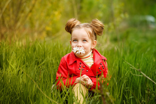 Little Girl Is Sniffing Flower In Meadow