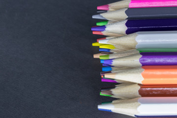 Color pencils of different colors lie on a gray background