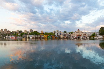Naklejka premium City landscape with buildings, yachts, and floating houses along the shore. Sunrise at False Creek waterfront, Vancouver, British Columbia, Canada.