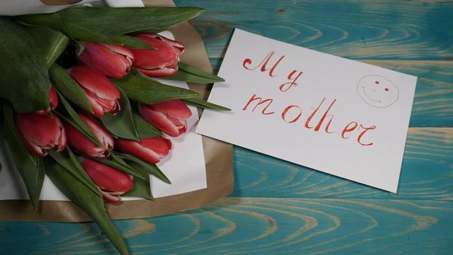 Top view of a My Mother message note and Tulips flowers bouquet on a wooden table. Love relationship concept. Mother day. Shot in 4 k