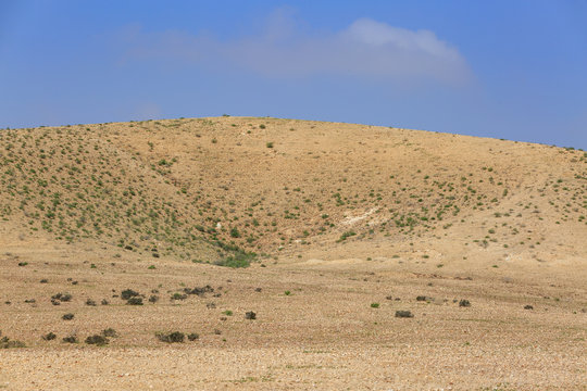 Far hill with small valley in desert under sky